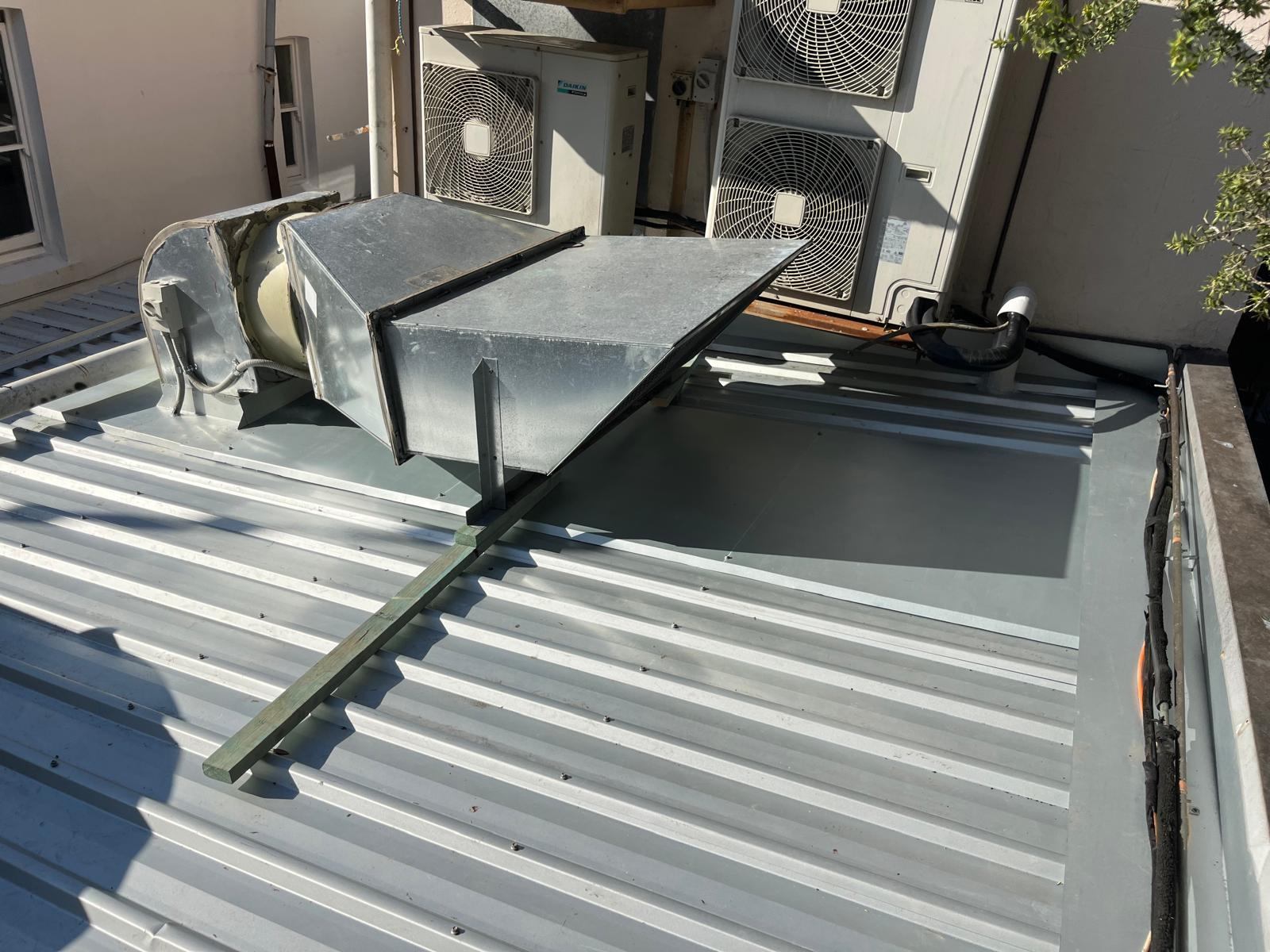 A long-run commercial metal roof with plant and ducting